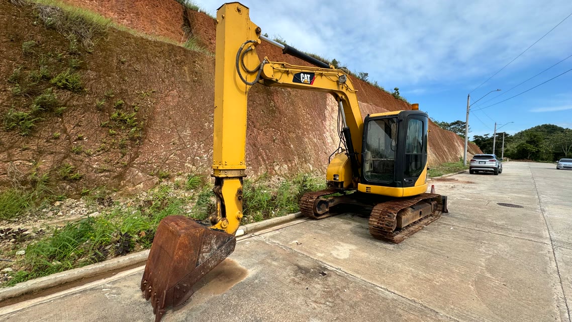 Excavadora CAT con el brazo elevado, vista frontal